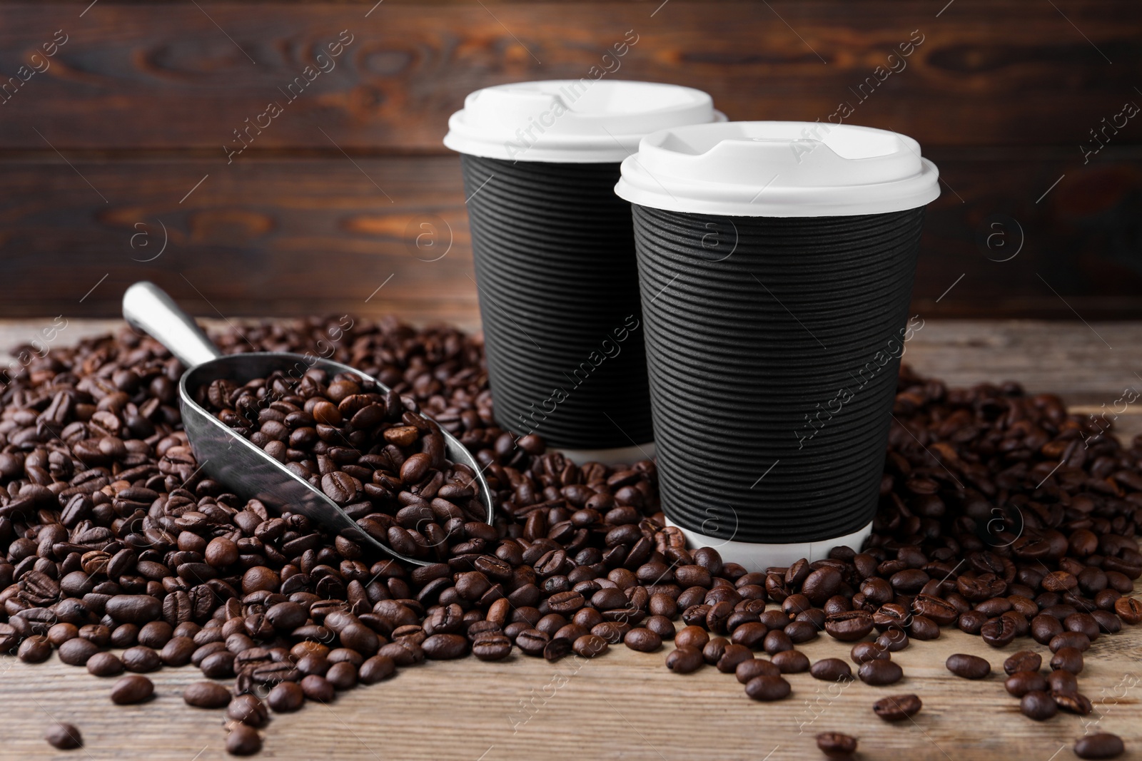 Photo of Coffee to go. Paper cups, roasted beans and scoop on wooden table