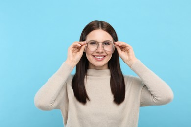 Portrait of woman in stylish eyeglasses on light blue background