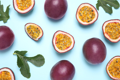 Photo of Fresh ripe passion fruits (maracuyas) with green leaves on light blue background, flat lay
