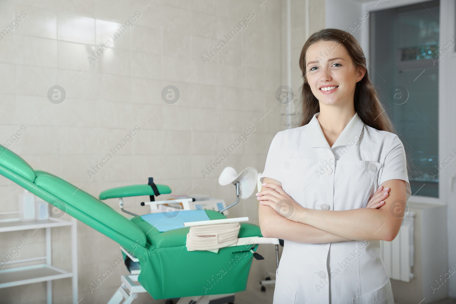 Photo of Portrait of smiling young gynecologist at workplace in clinic. Space for text