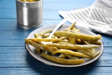 Photo of Canned green beans on blue wooden table, closeup