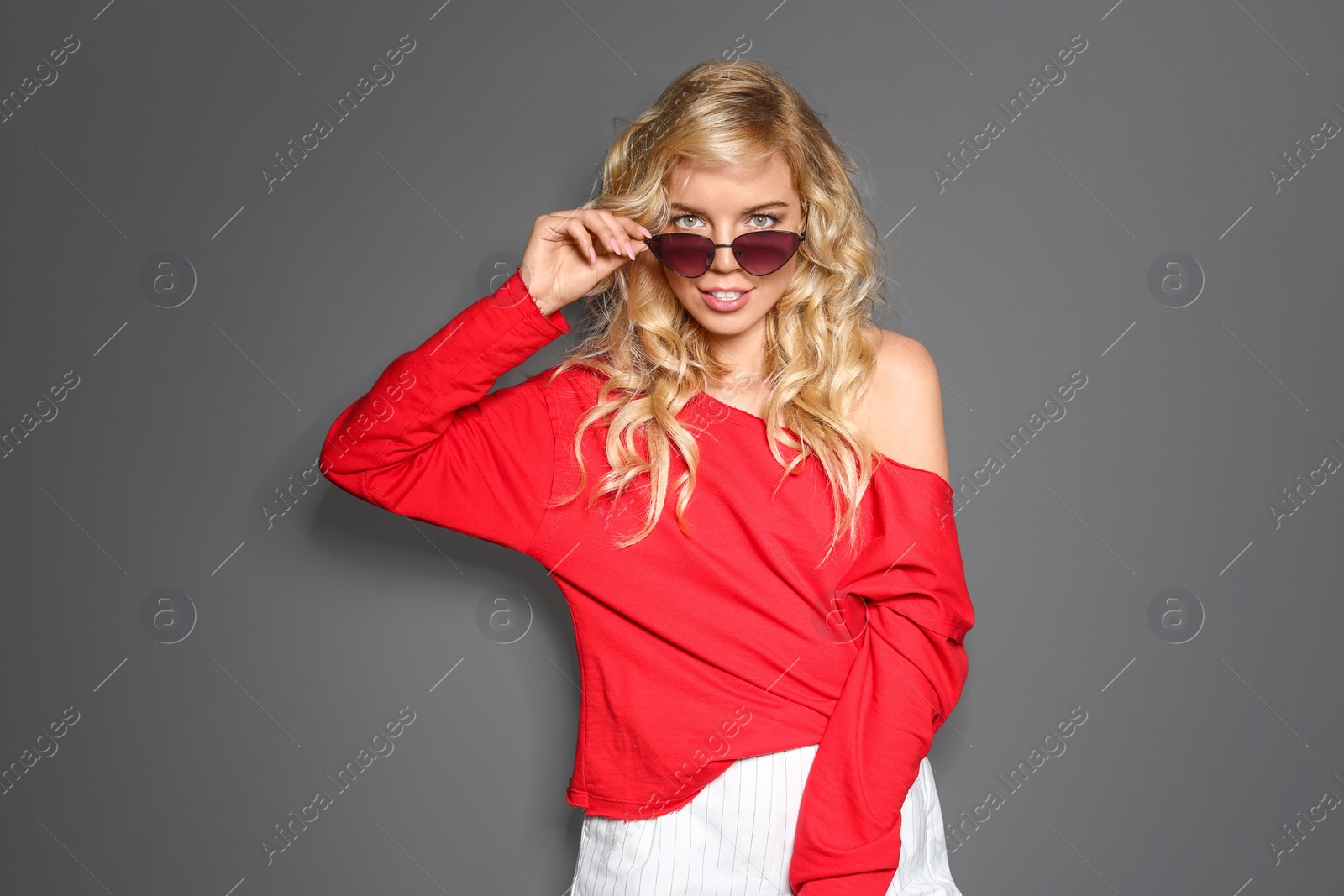 Photo of Stylish young woman with sunglasses posing on grey background