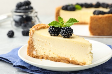 Photo of Piece of delicious cheesecake with blackberries on table, closeup