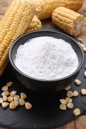 Photo of Bowl with corn starch, ripe cobs and kernels on table, closeup
