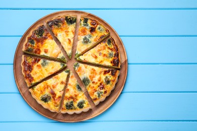 Photo of Delicious homemade quiche with salmon and broccoli on light blue wooden table, top view. Space for text