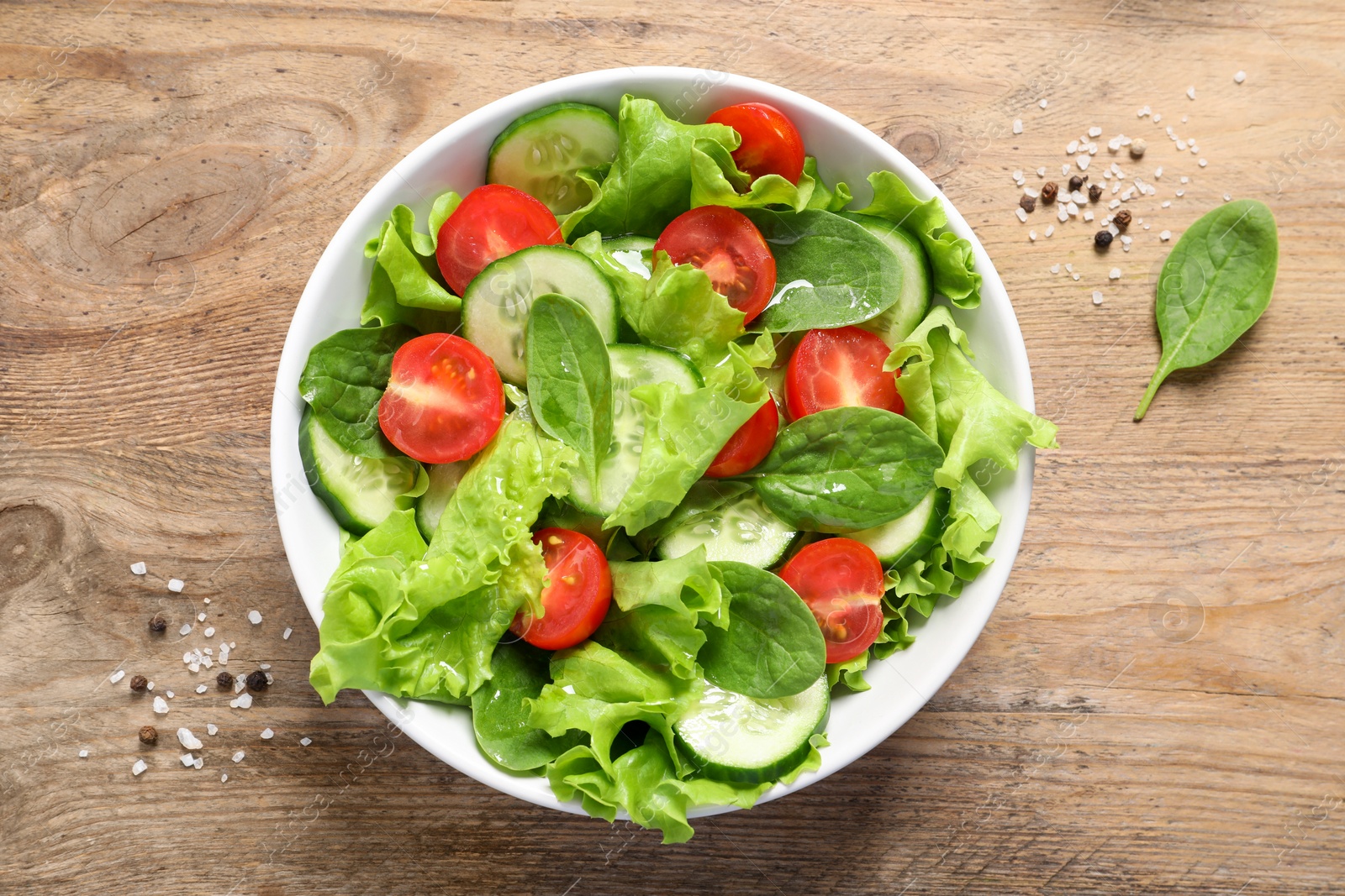 Photo of Delicious vegetable salad on wooden table, flat lay