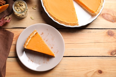 Photo of Flat lay composition with piece of fresh delicious homemade pumpkin pie and space for text on wooden background