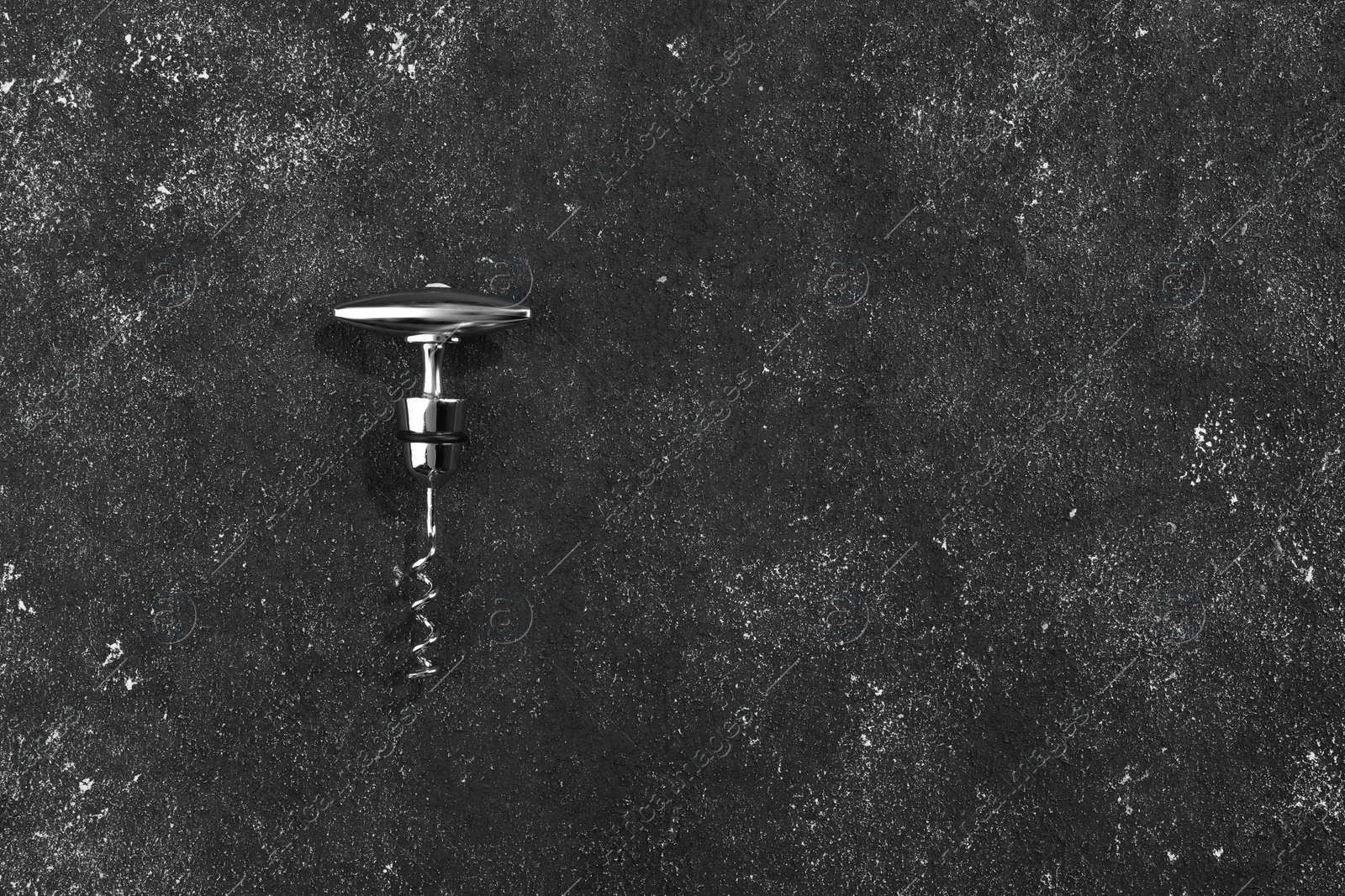 Photo of One corkscrew on grey textured table, top view. Space for text