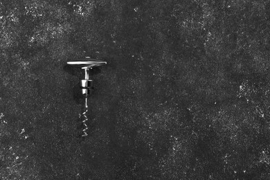 Photo of One corkscrew on grey textured table, top view. Space for text