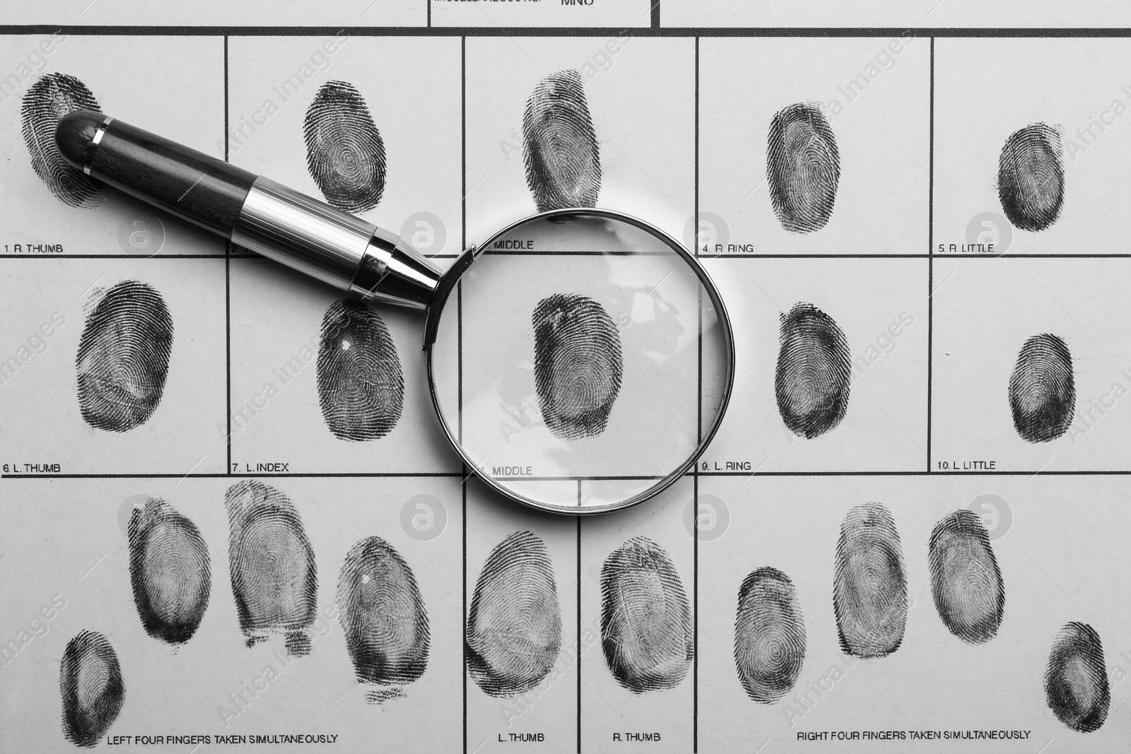 Photo of Magnifying glass and criminal fingerprint card, top view