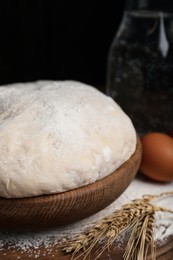 Photo of Dough in wooden bowl against black background. Sodawater bread recipe