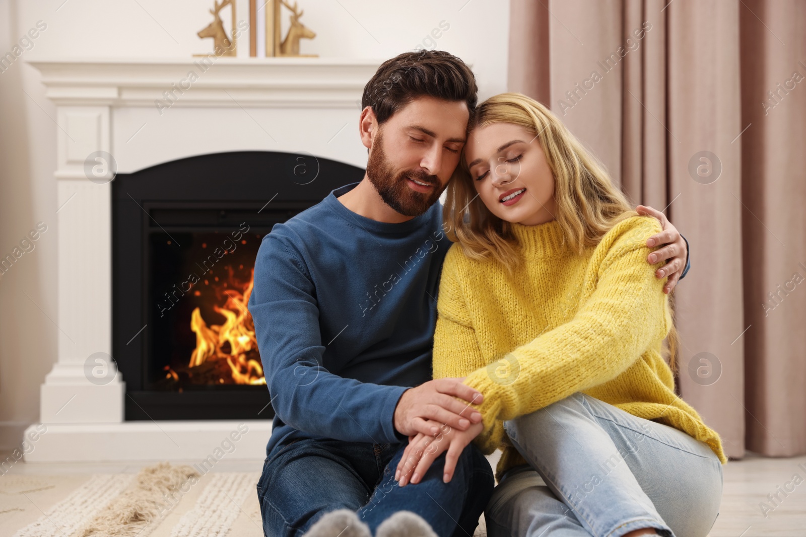 Photo of Lovely couple spending time together near fireplace indoors