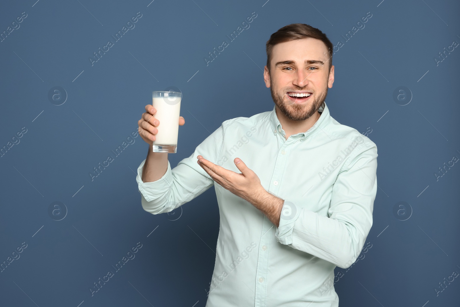 Photo of Young man with glass of tasty milk on color background