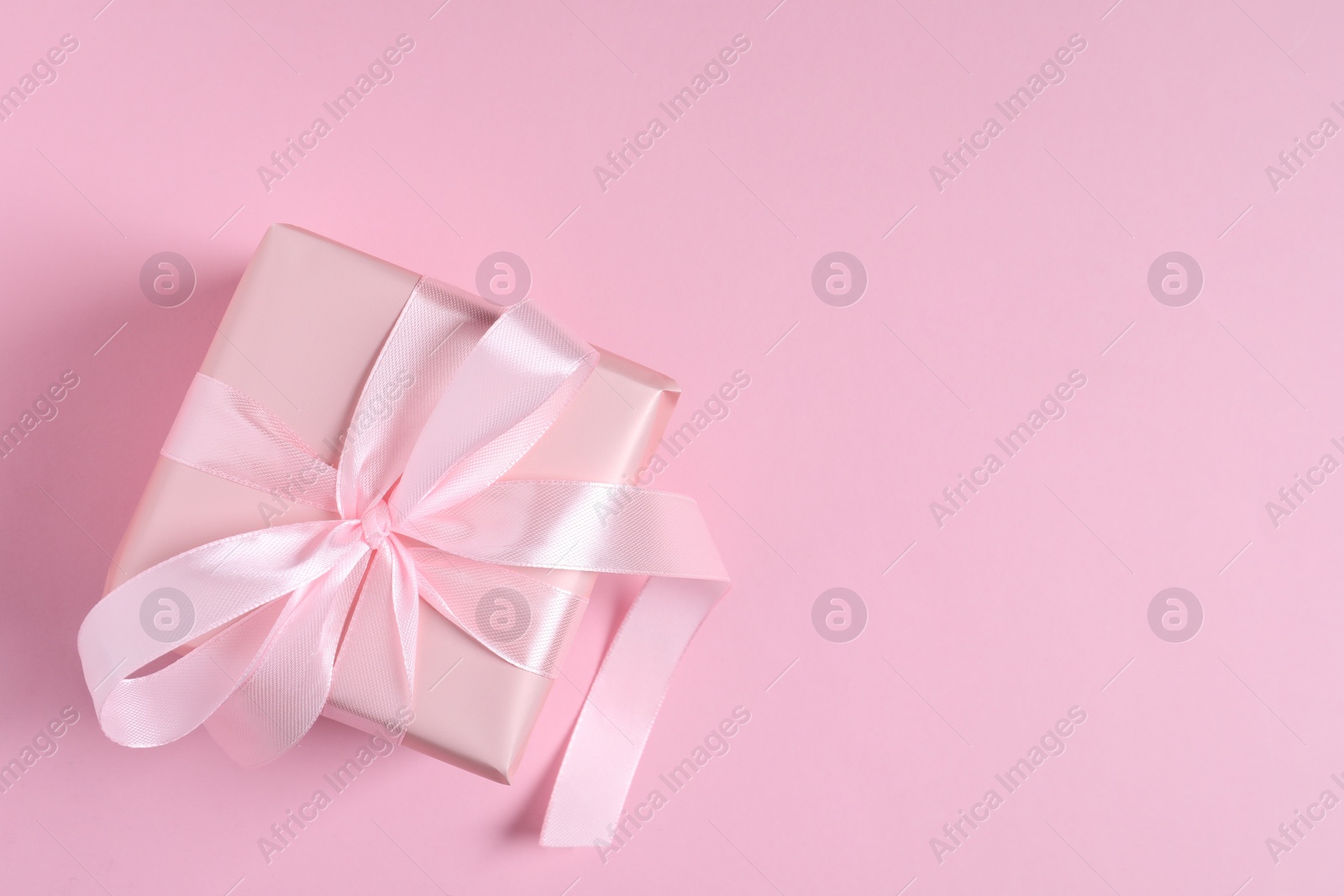 Photo of Gift box on pink background, top view. Space for text