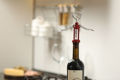 Wine bottle with metal corkscrew in kitchen. Space for text