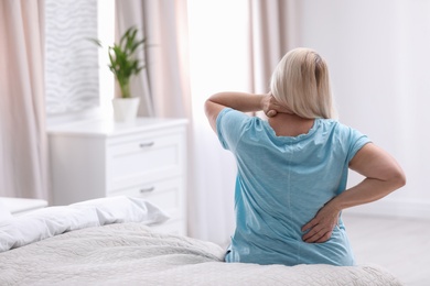 Senior woman suffering from back pain at home