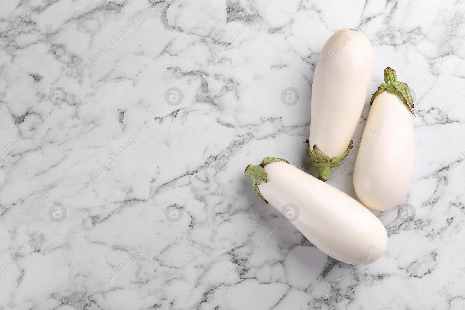 Photo of Ripe white eggplants on marble table, flat lay. Space for text