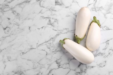 Ripe white eggplants on marble table, flat lay. Space for text