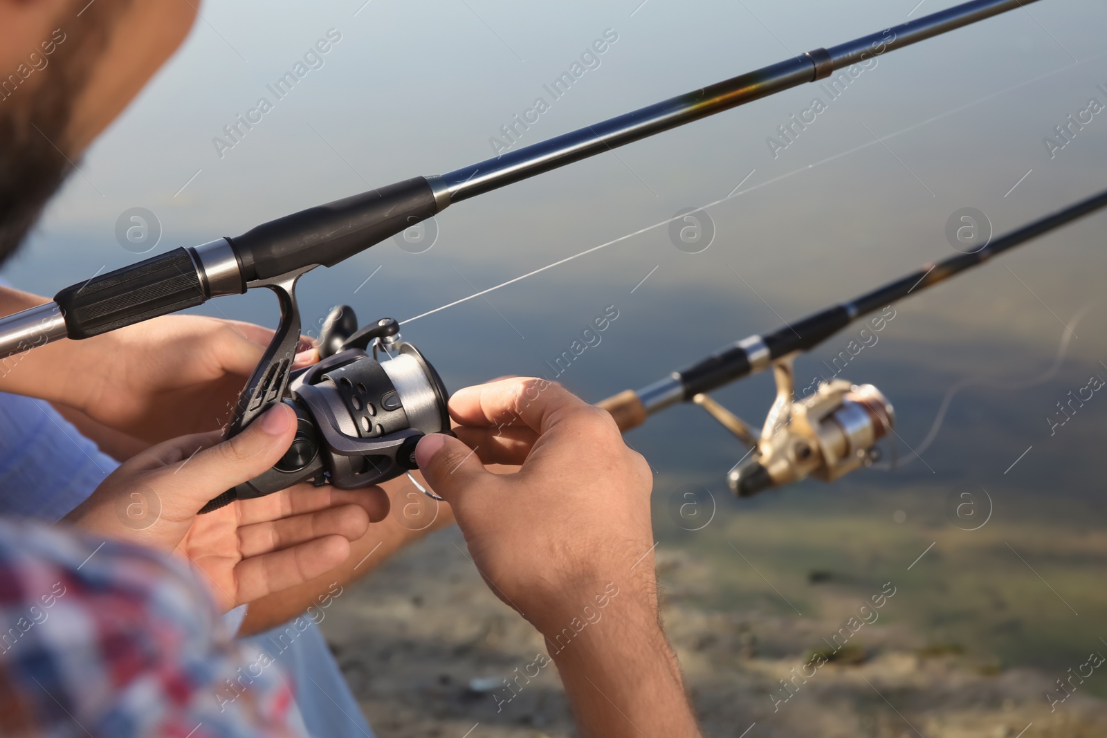 Photo of Men fishing at riverside on sunny day, closeup