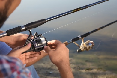 Men fishing at riverside on sunny day, closeup