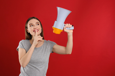 Young woman with megaphone on red background. Space for text