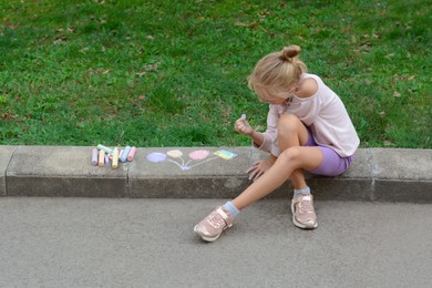 Little child drawing balloons and ukrainian flag with chalk on curb outdoors, space for text