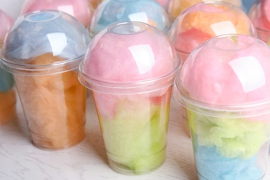 Photo of Many plastic cups with tasty cotton candies on white wooden table