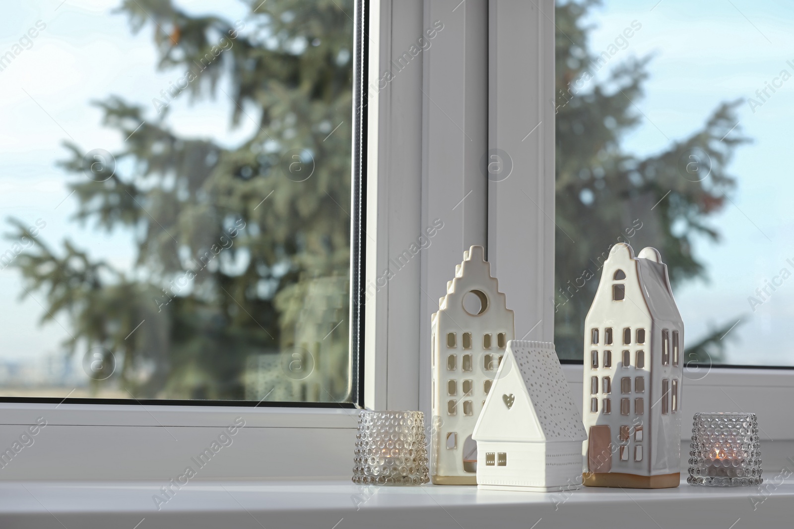 Photo of Beautiful house shaped candle holders on windowsill indoors, space for text