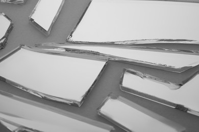 Photo of Shards of broken mirror on grey background, closeup