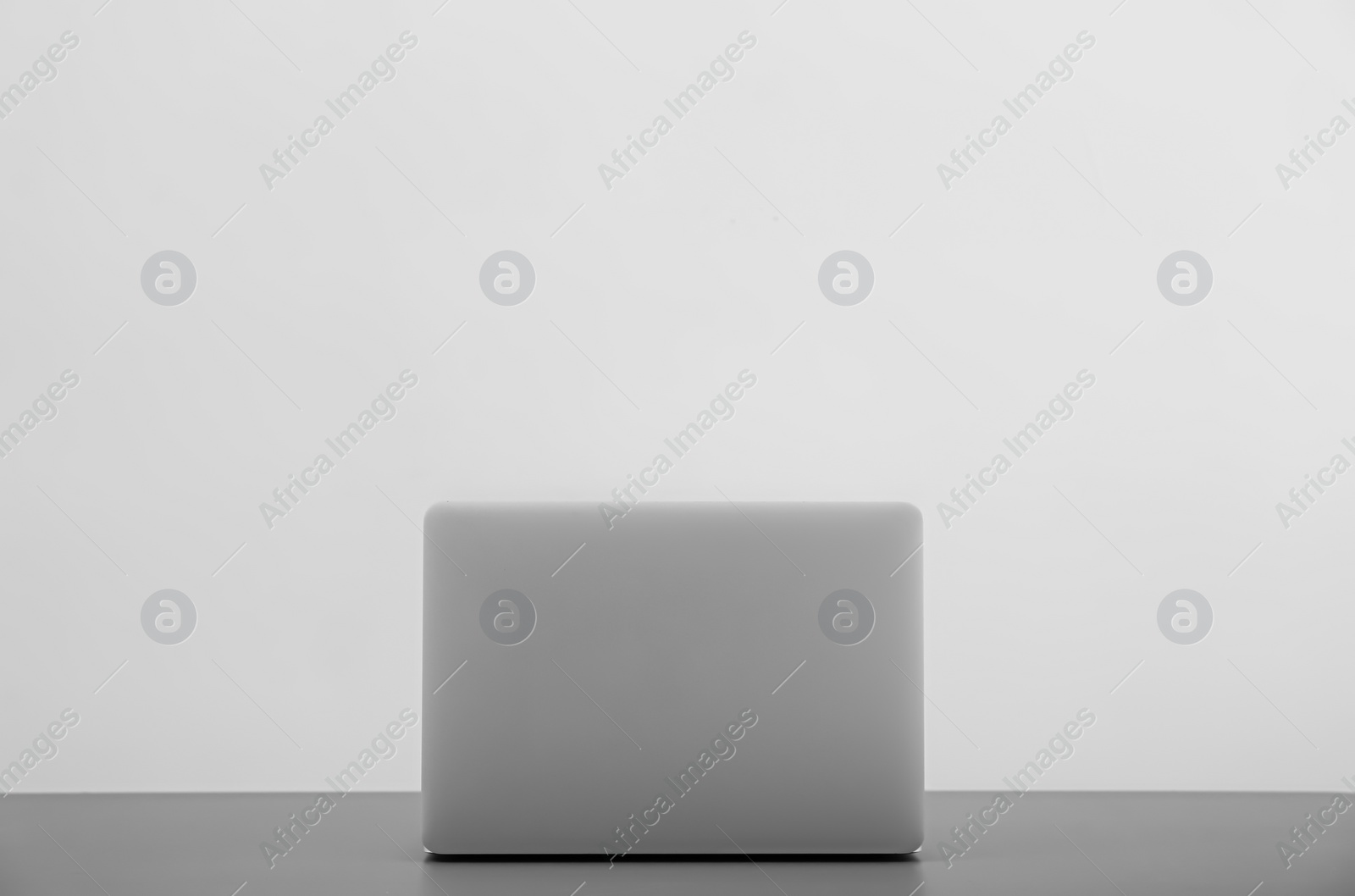 Photo of Modern laptop on table against light background