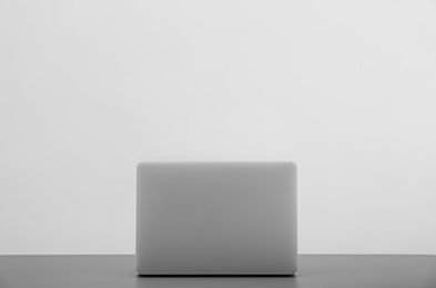 Photo of Modern laptop on table against light background