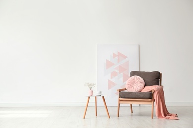 Photo of Stylish living room interior with comfortable armchair and wooden table near white wall. Space for text