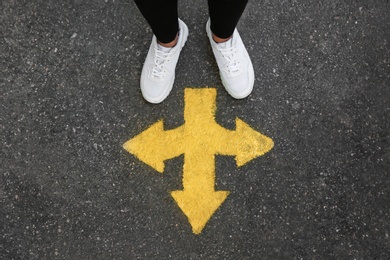 Photo of Woman standing near arrow on asphalt, top view