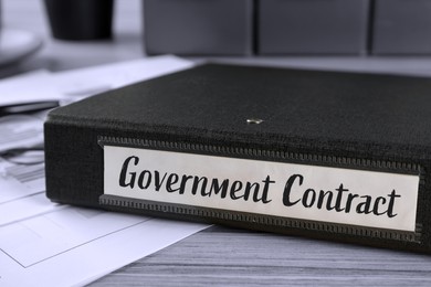 Black folder with Government Contract label on desk in office, closeup