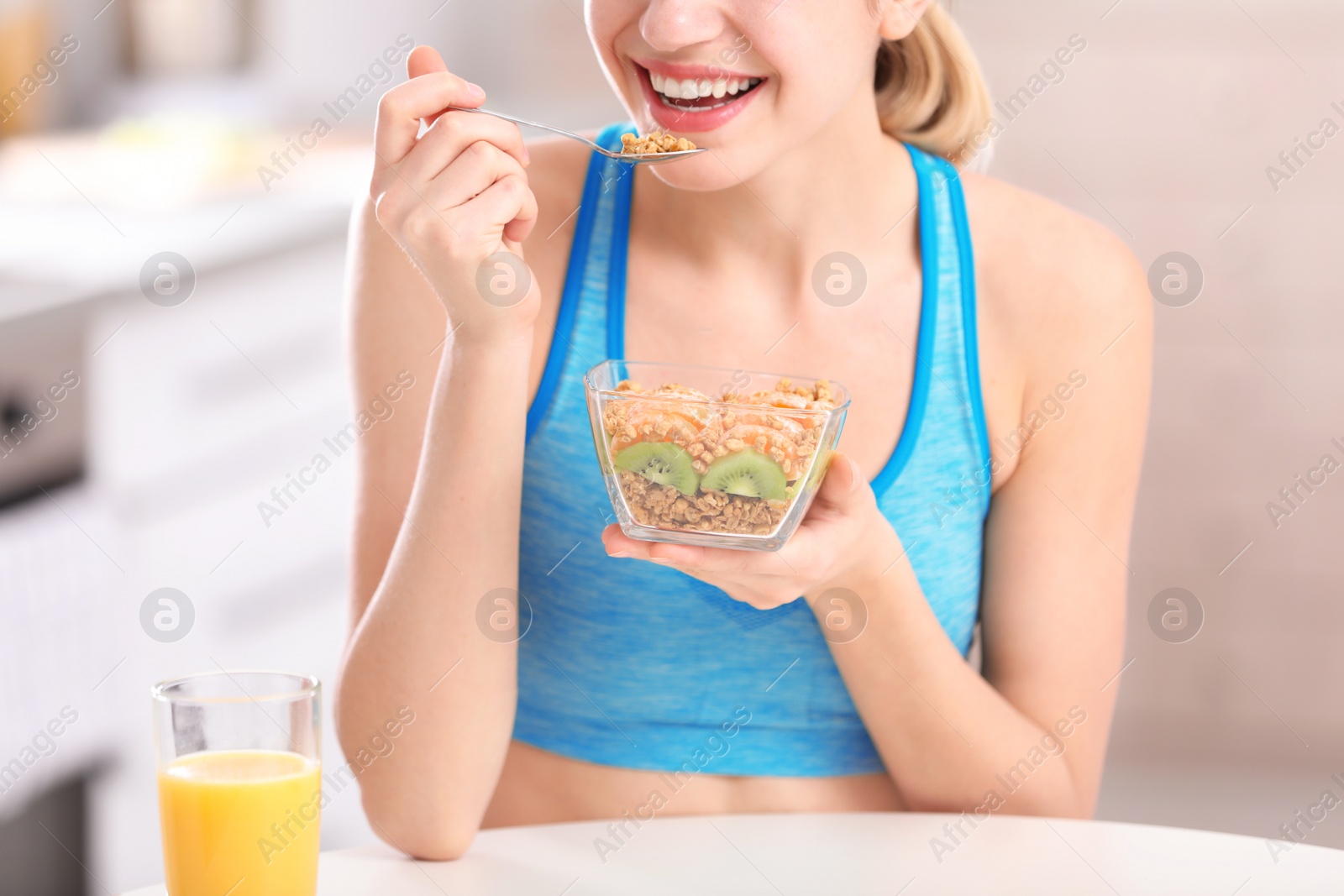 Photo of Young woman in fitness clothes having healthy breakfast at home, closeup