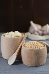 Photo of Dehydrated garlic granules, fresh cloves and spoon on grey wooden table