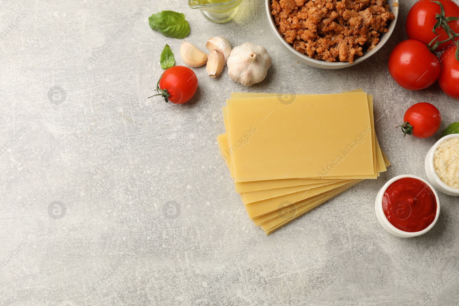 Photo of Flat lay composition with products for cooking lasagna on grey textured table. Space for text