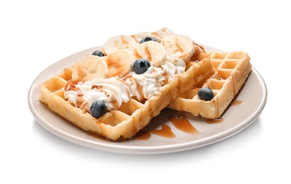 Photo of Plate with yummy waffles, whipped cream, blueberries and banana on white background