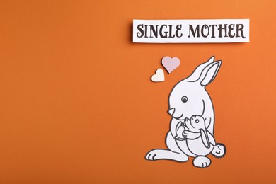 Photo of Being single mother concept. Rabbit with baby made of paper on orange background, flat lay and space for text