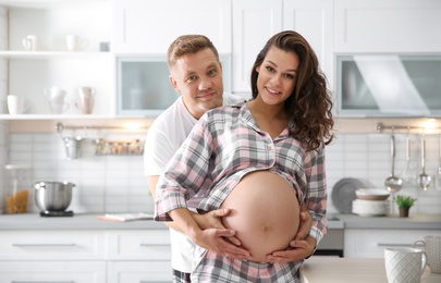 Pregnant woman with her husband in kitchen. Happy young family