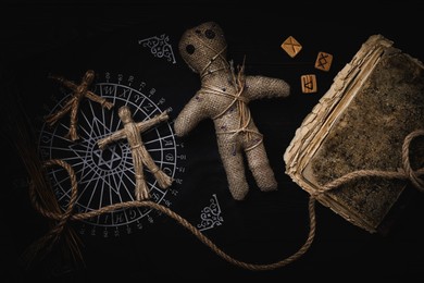 Image of Voodoo doll with pins surrounded by ceremonial items on table, flat lay