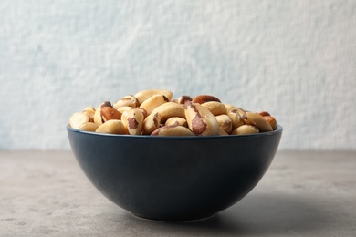 Photo of Bowl with tasty Brazil nuts on grey table