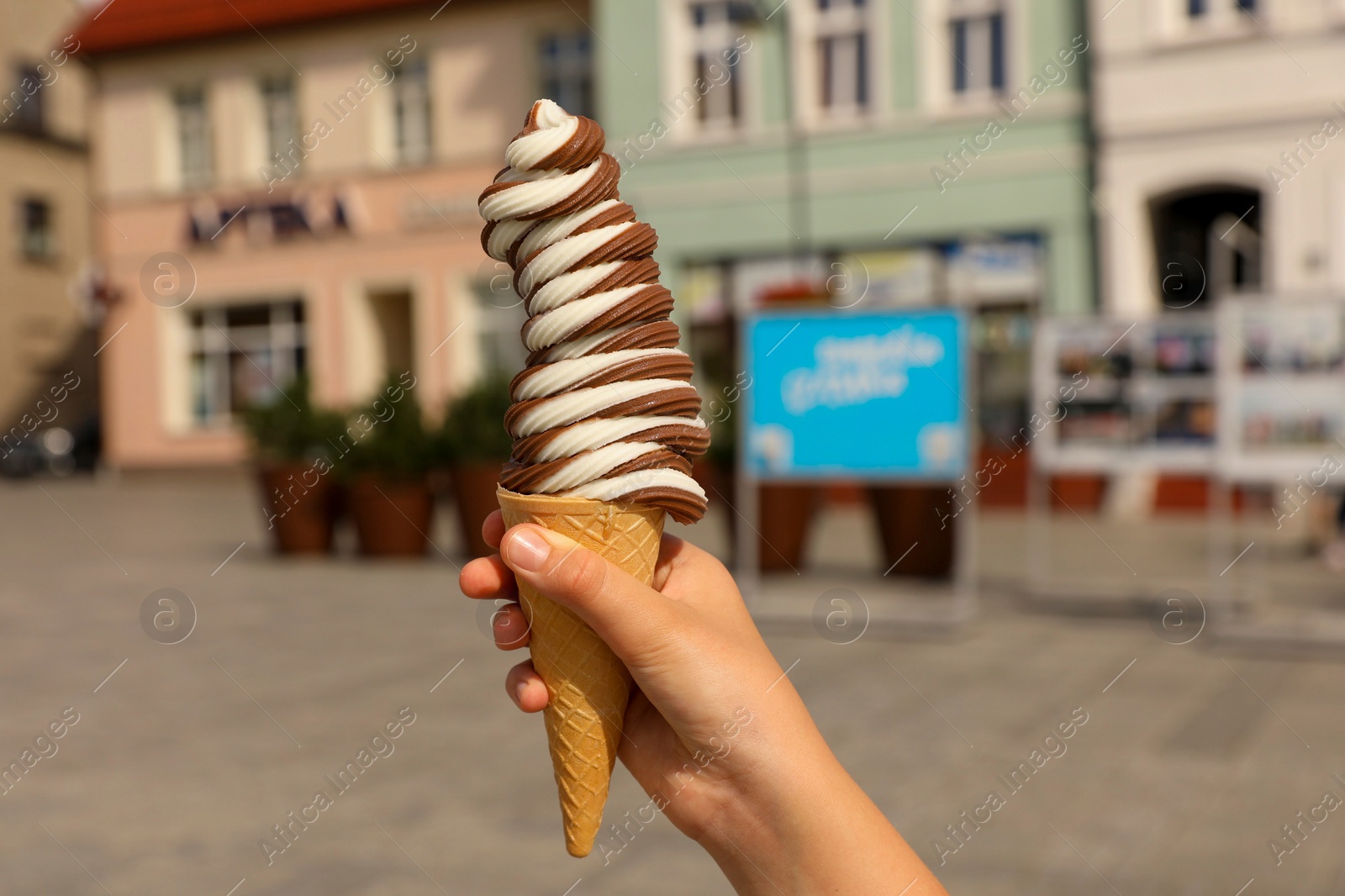 Photo of Woman holding delicious ice cream cone in city, closeup