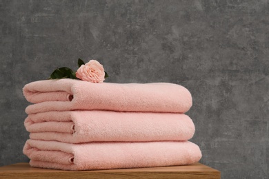 Stack of soft clean towels with beautiful flower on table. Space for text