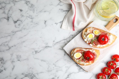 Flat lay composition with delicious bruschettas on white marble table, space for text