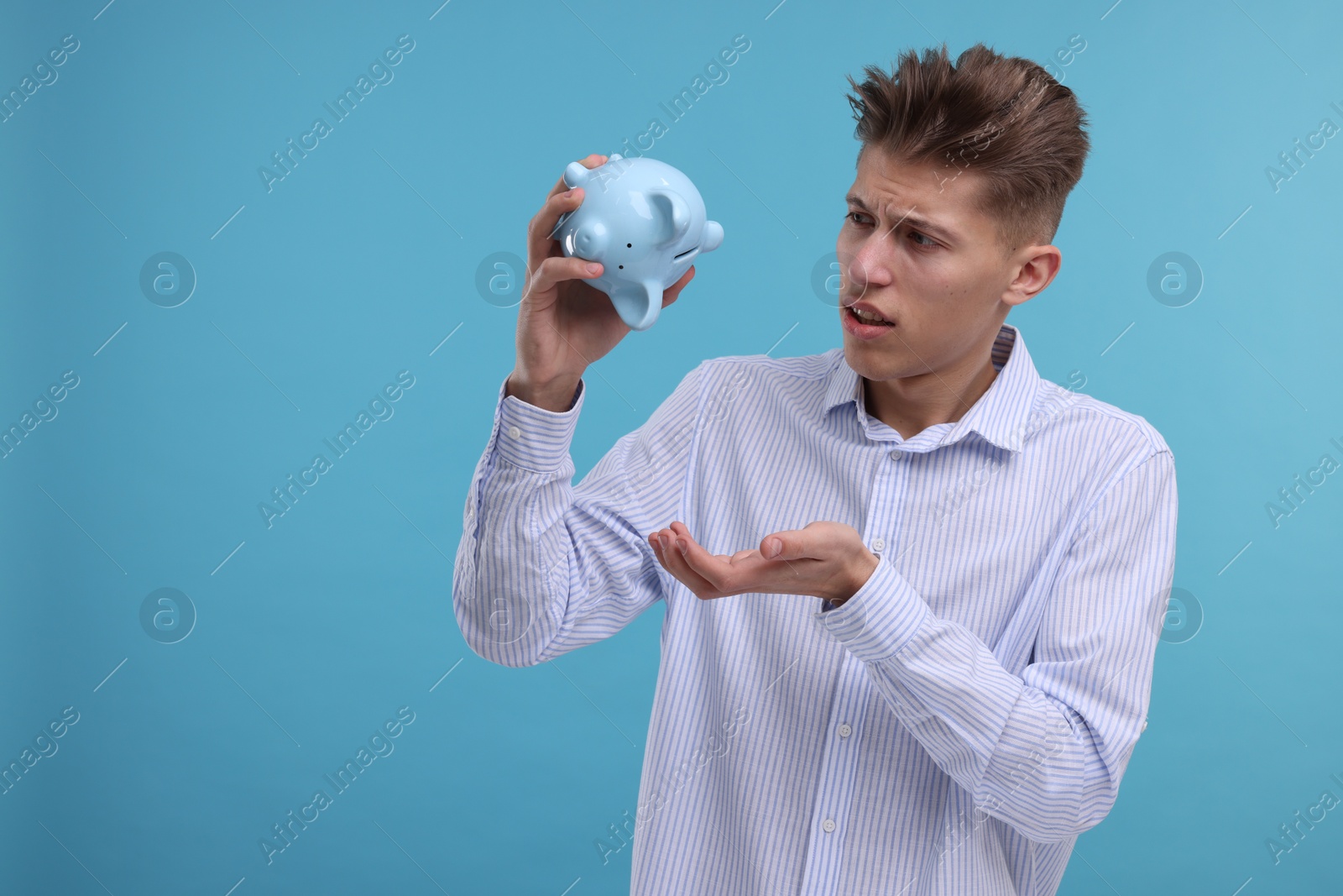 Photo of Upset man with piggy bank on light blue background. Space for text