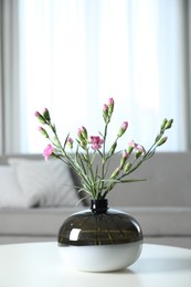 Photo of Vase with beautiful carnation flowers on table in living room, space for text. Stylish element of interior design