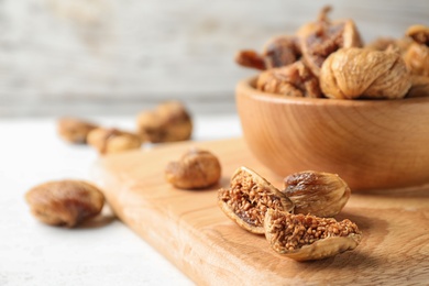 Photo of Wooden board with tasty dried figs on light table. Space for text