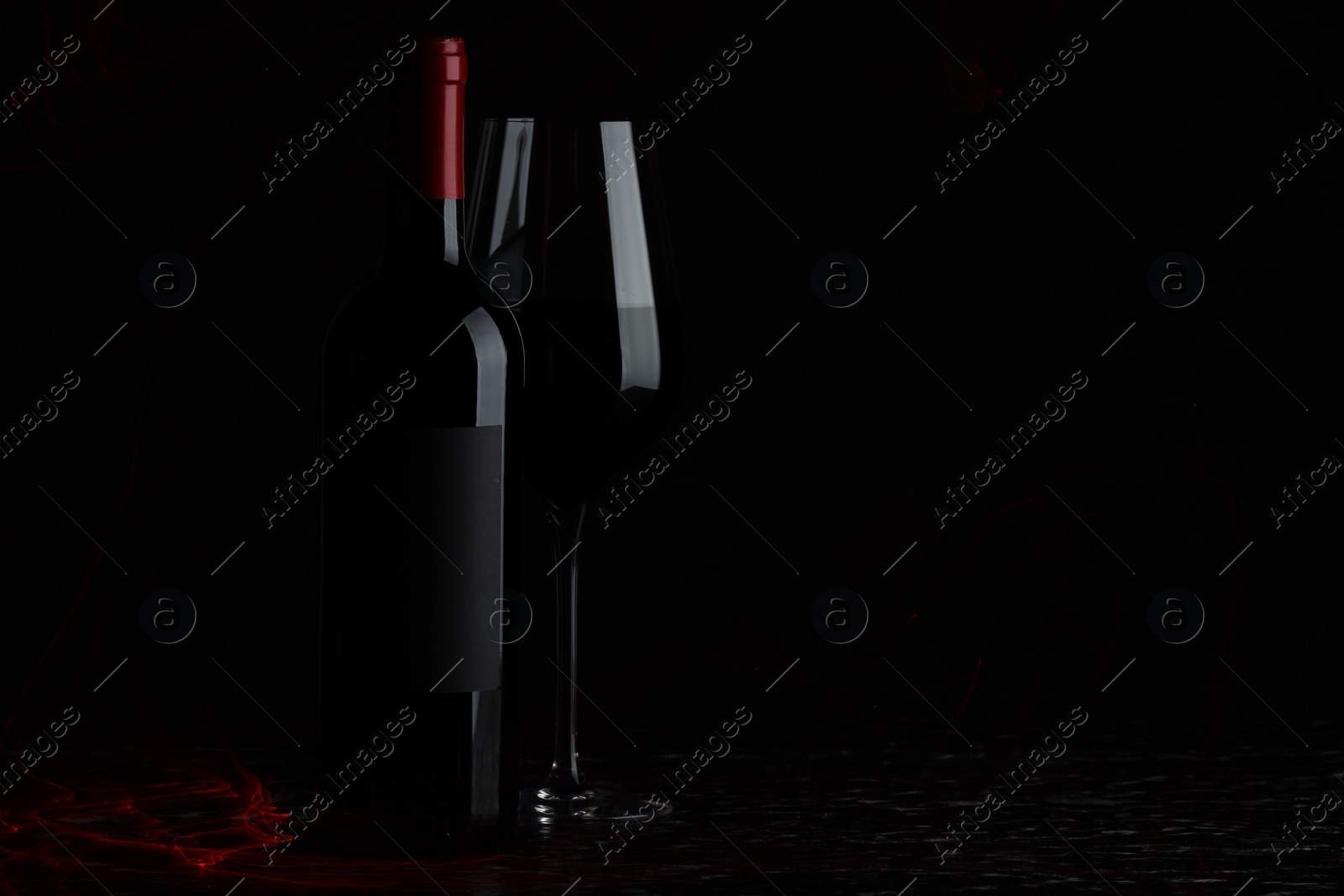 Photo of Tasty wine in glass and bottle on black background, space for text