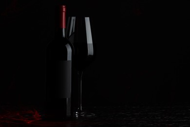 Photo of Tasty wine in glass and bottle on black background, space for text